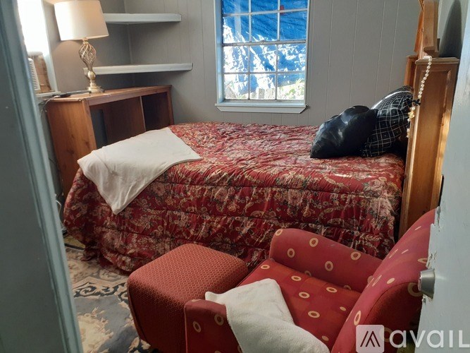 A bedroom with a red bed and a red chair.