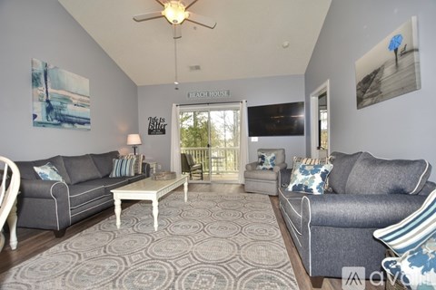 A living room with a grey couch, a white coffee table, and a rug with a pattern.
