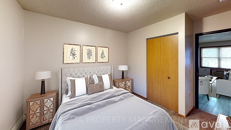 A bedroom with a bed, two lamps, and a wooden door.