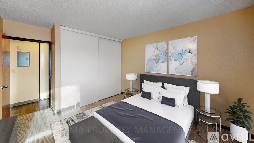 A bedroom with a bed, two lamps, and a painting on the wall.