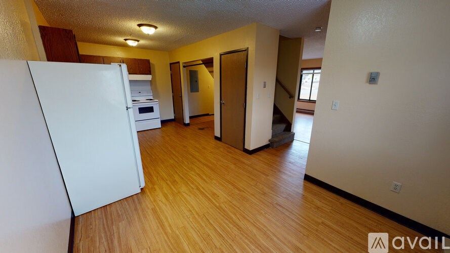 A kitchen with a white refrigerator and wooden floors.