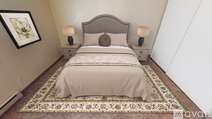 A bedroom with a bed, two lamps, and a framed picture on the wall.