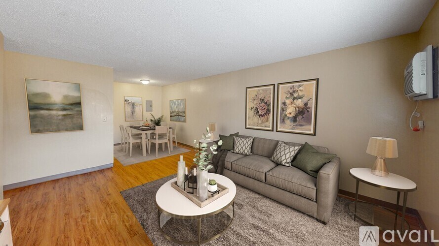 A living room with a grey couch, a coffee table, and a painting on the wall.
