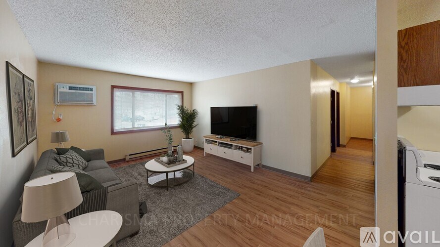 A living room with a grey couch, a white coffee table, and a television.