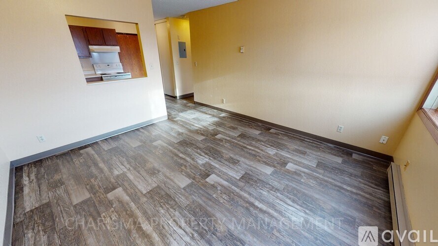 A room with wooden flooring and a small kitchenette in the corner.