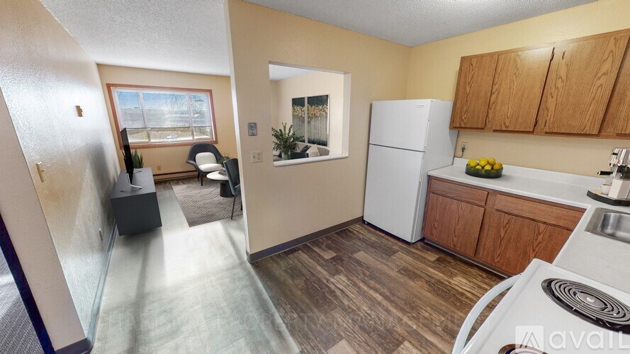A kitchen with a white refrigerator, wooden cabinets, and a window with a view of the outdoors.