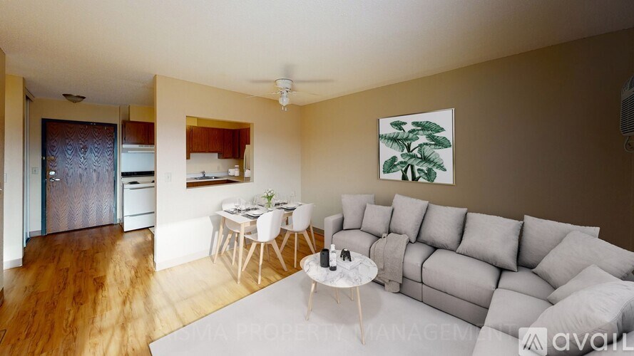 A living room with a grey couch, a white coffee table, and a painting of a tree on the wall.