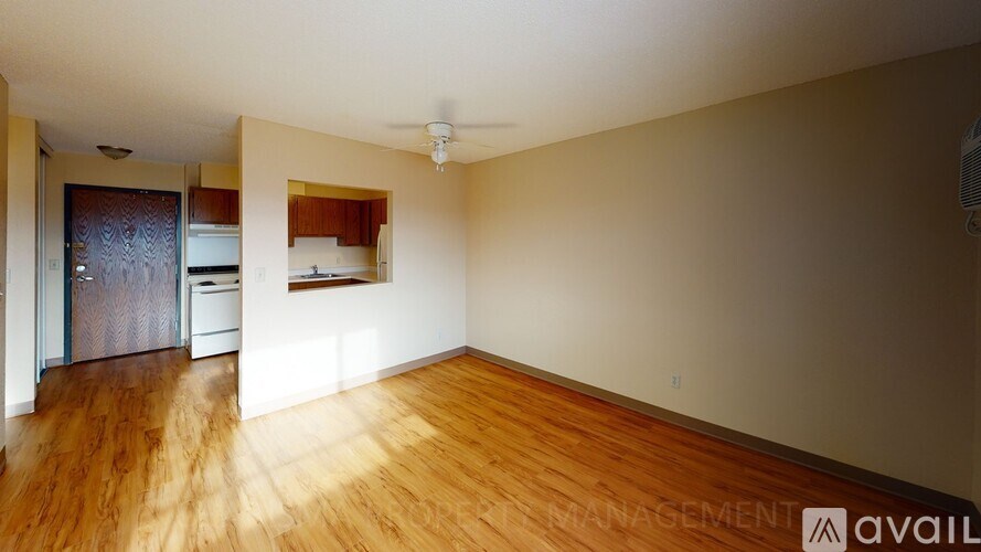 A spacious room with wooden floors and a ceiling fan.