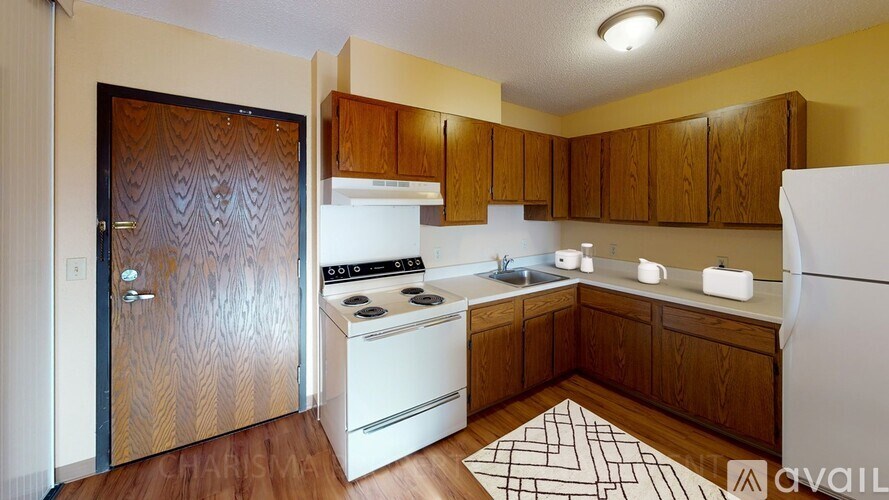 A kitchen with a white fridge, white stove and wooden cabinets.