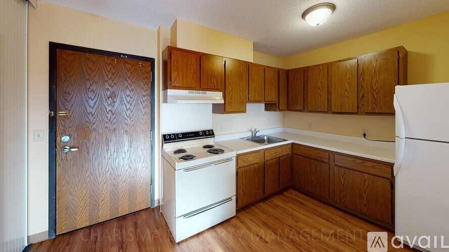 A kitchen with a white fridge, white stove and wooden cabinets.