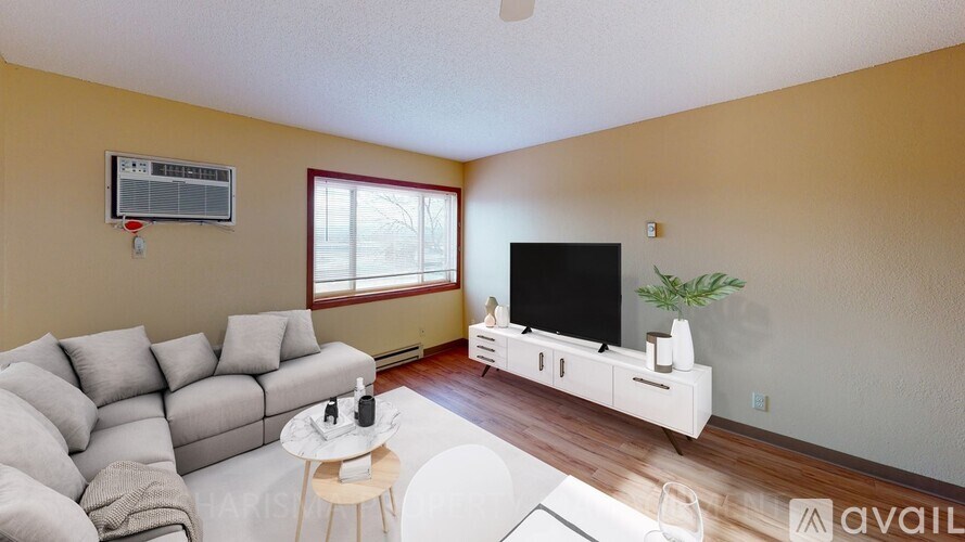 A living room with a grey sofa, a white coffee table, and a white TV stand.
