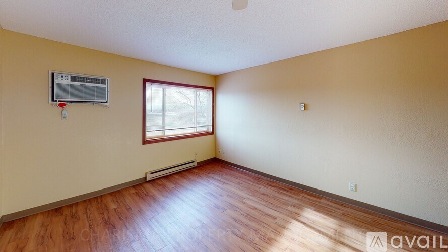 A room with wooden flooring and a window with blinds.