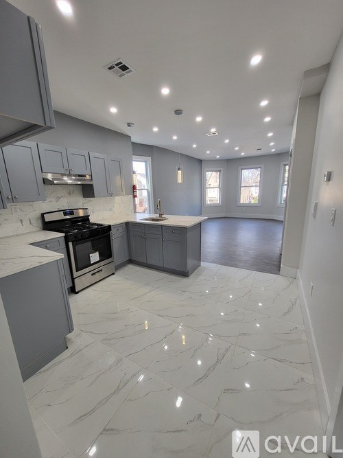 A modern kitchen with marble flooring and grey cabinets.