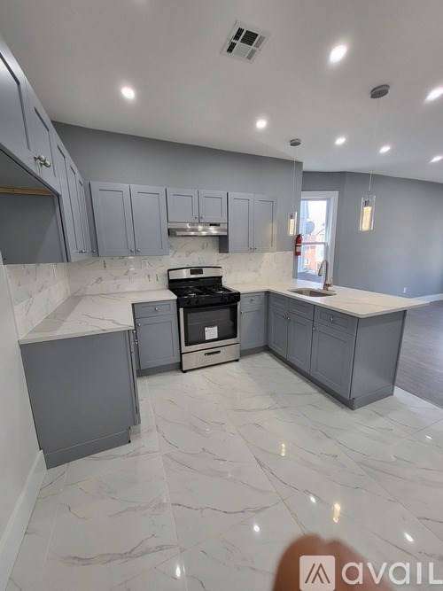 A kitchen with a marble floor and grey cabinets.
