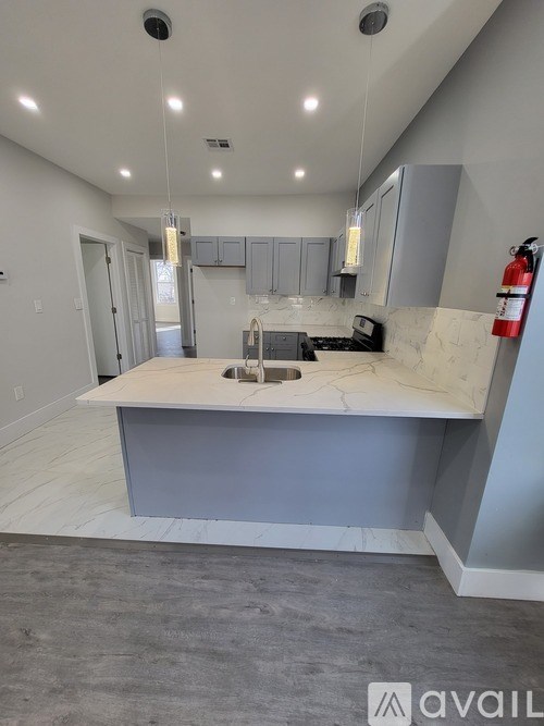 A kitchen with a marble countertop and grey cabinets is available for rent.