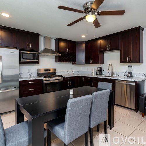 A kitchen with dark wood cabinets and a black table.