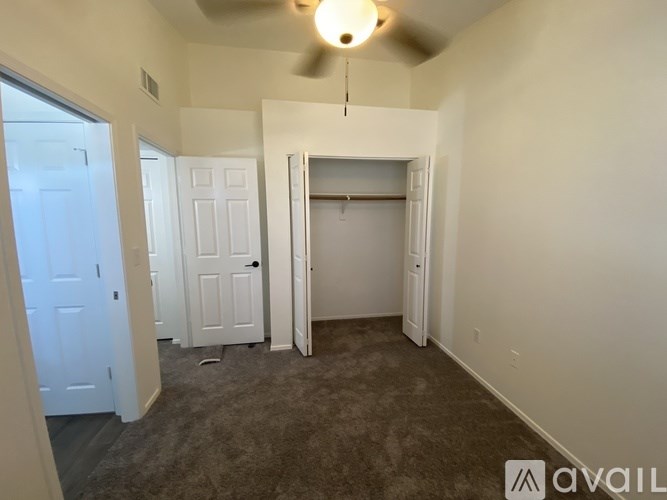 A room with a ceiling fan and carpeted floor.