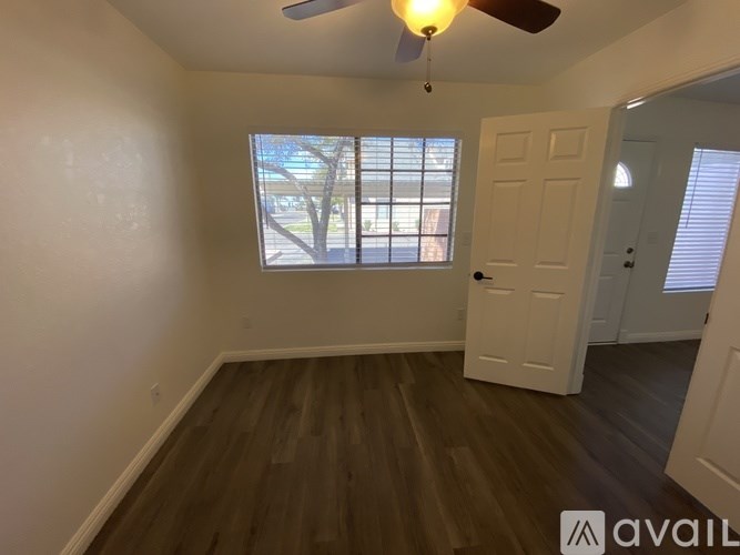 A room with a ceiling fan and a window with blinds.