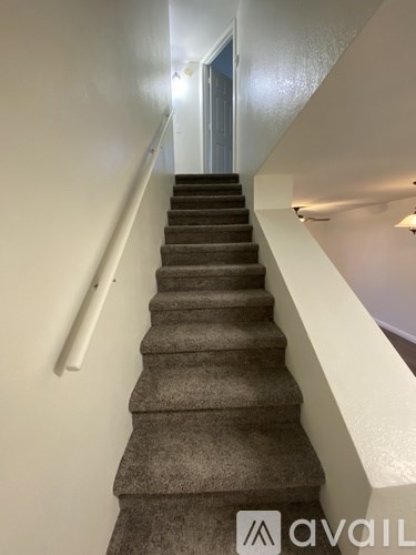 A staircase with a carpeted runner and a white handrail.