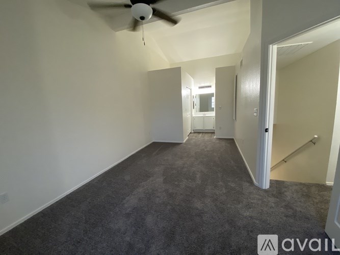 A room with a carpeted floor and a ceiling fan.