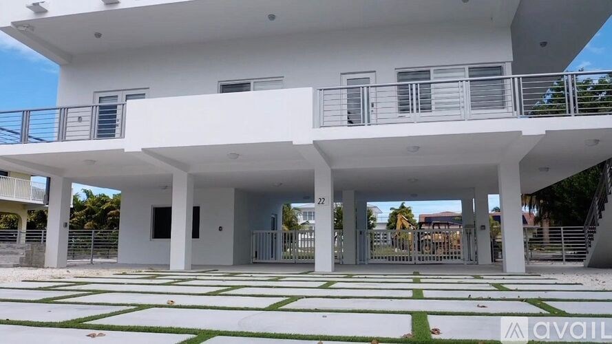 A white two-story building with balconies and a green lawn in front.