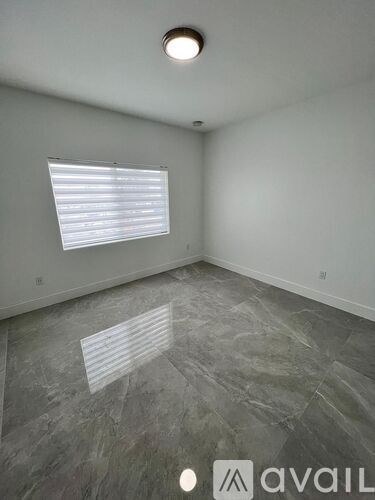 A room with grey marble flooring and a window with blinds.