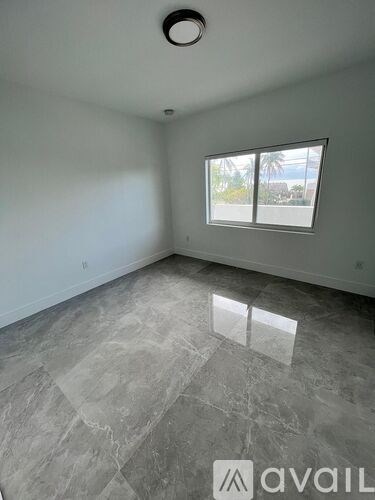 A room with a large window and grey tiled flooring.