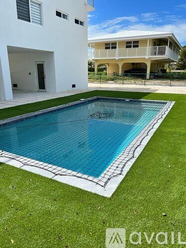 A white house with a blue pool in front.