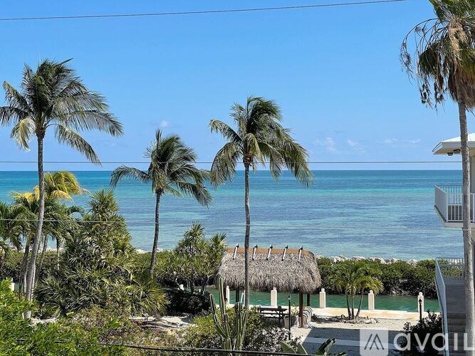 A beautiful beach view with palm trees and a thatched roof hut.