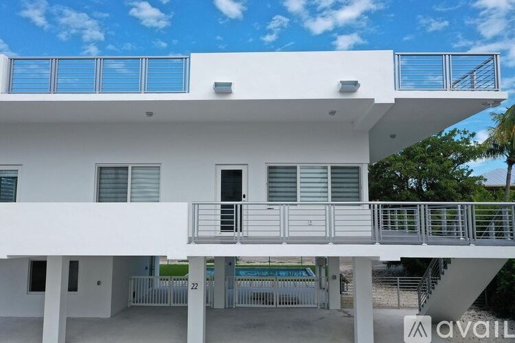 A white two-story house with a balcony on the upper floor.