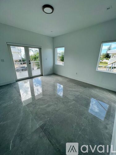A spacious room with grey marble flooring and a large window.