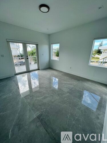 A spacious room with grey marble flooring and a large window.