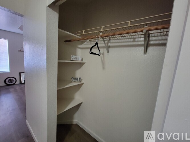 A white closet with a shelf and clothes hangers.
