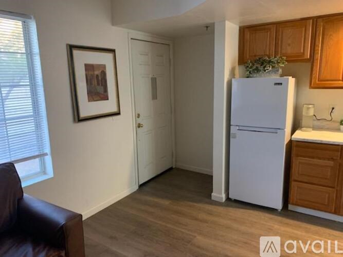 A kitchen area with a white refrigerator, wooden cabinets, and a brown leather chair.