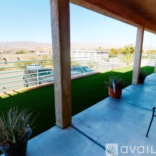 A balcony with a table and chairs overlooking a parking lot.