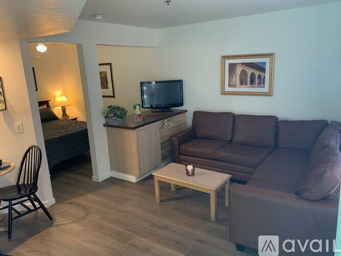 A living room with a brown couch, a chair, a coffee table, and a television.