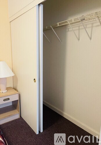 A white door is open to a room with a white wall and a white shelf with a lamp on it.