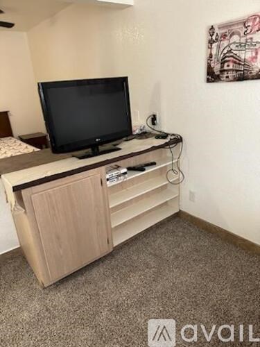 A black television is on a wooden stand in a room.