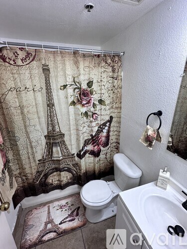 A bathroom with a shower curtain featuring the Eiffel Tower and roses.