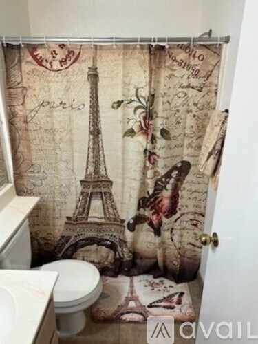 A bathroom with a shower curtain featuring the Eiffel Tower.