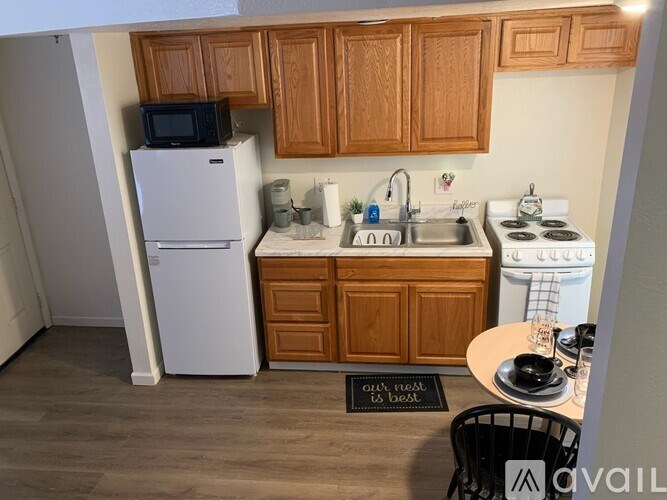 A small kitchen with a white refrigerator, a sink, a stove, and wooden cabinets.