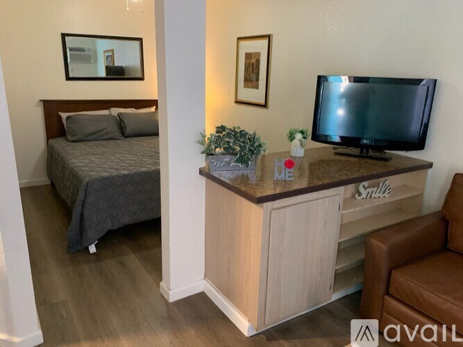 A bedroom with a bed, a desk with a television, and a chair.