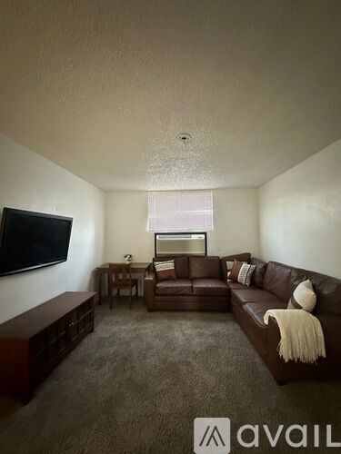 A living room with a brown couch and a flat screen TV mounted on the wall.
