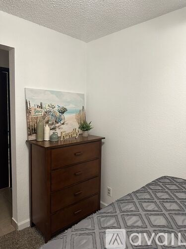 A bedroom with a bed, dresser, and a painting on the wall.