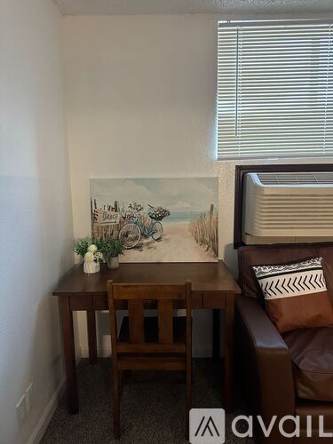 A room with a brown couch, a wooden table, and a painting on the wall.