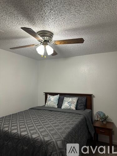 A bedroom with a bed, pillows, a ceiling fan, and a nightstand.