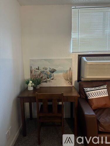 A brown couch sits in front of a painting of a beach scene.