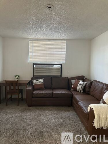 A living room with a brown leather couch and a small table.