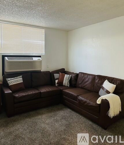 A brown leather couch with a white throw blanket on it.