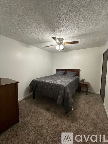 A bedroom with a bed, nightstand, and carpeted floor.